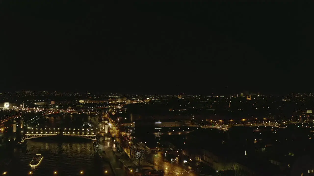 Aerial view of large city at night Forwards fly above illuminated Seine River waterfront Paris France