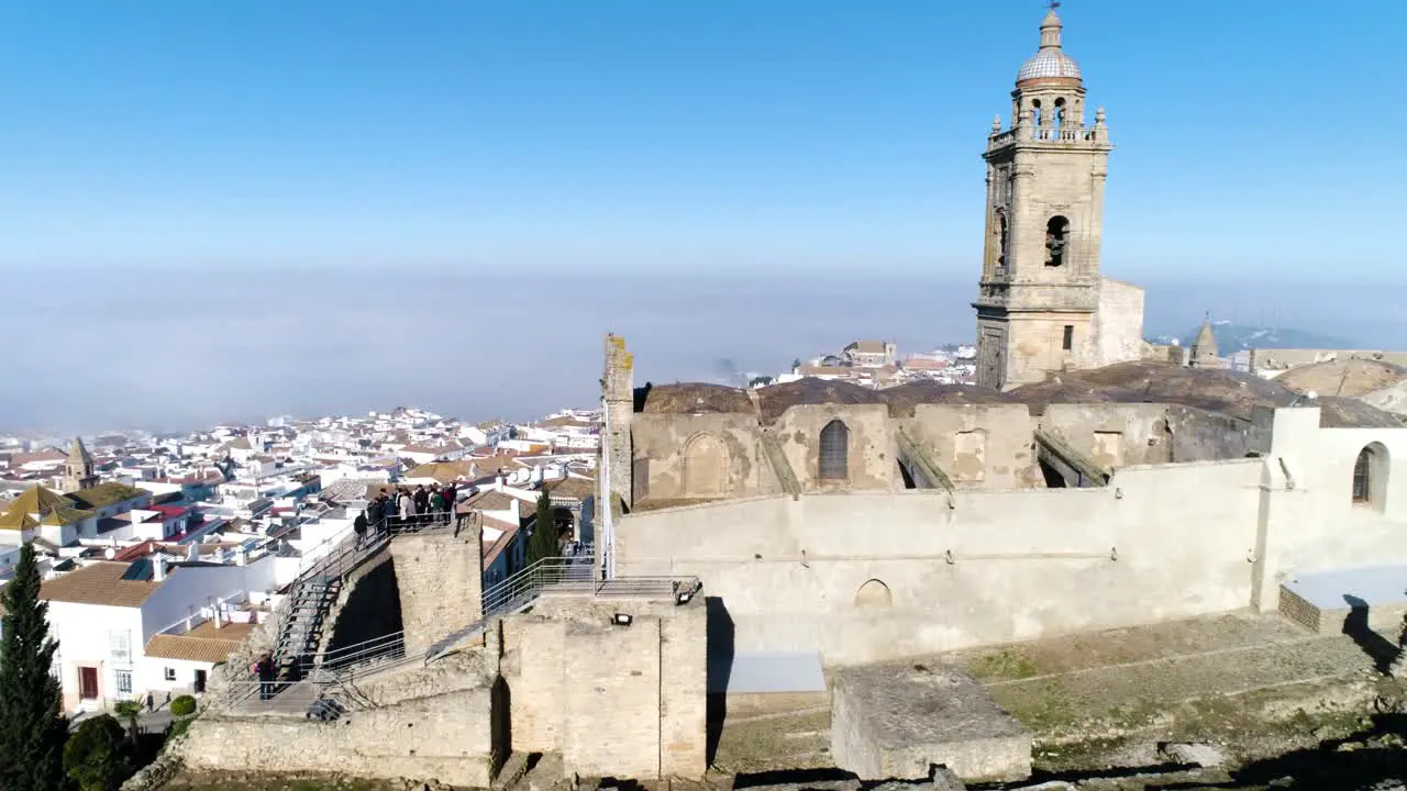 Aerial dolly shot of the church of santa maria in medina sidonia in andalucia in spain overlooking the historic old town with white buildings on a cloudless summer day