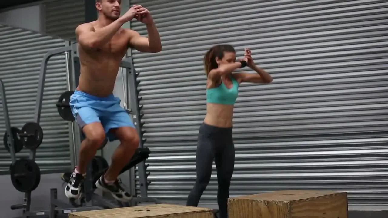 Fit couple doing set of box jumps