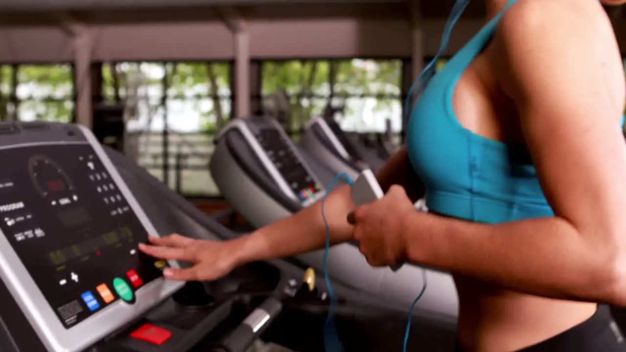 Smiling muscular woman running on treadmill