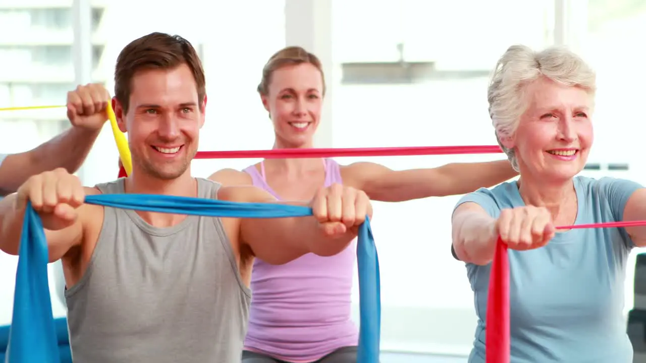 Fitness group sitting on exercise balls stretching resistance bands