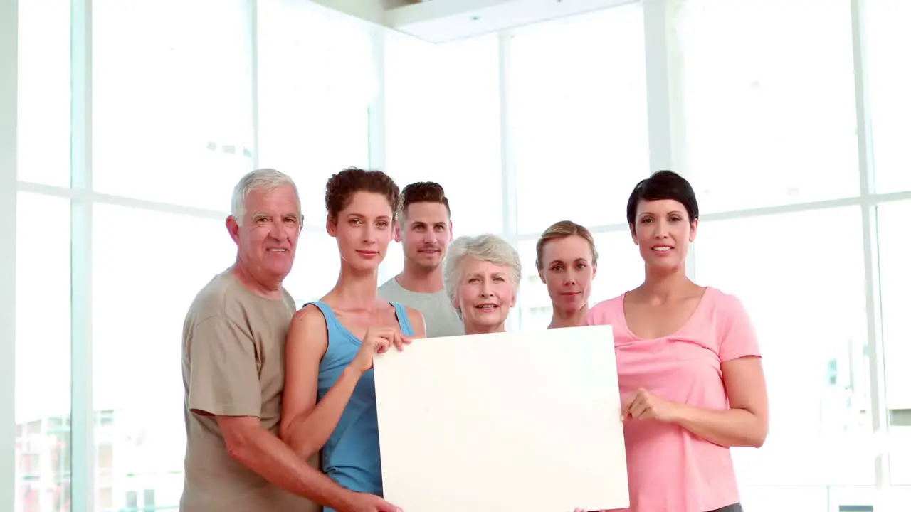 Fitness class holding a white poster an cheering