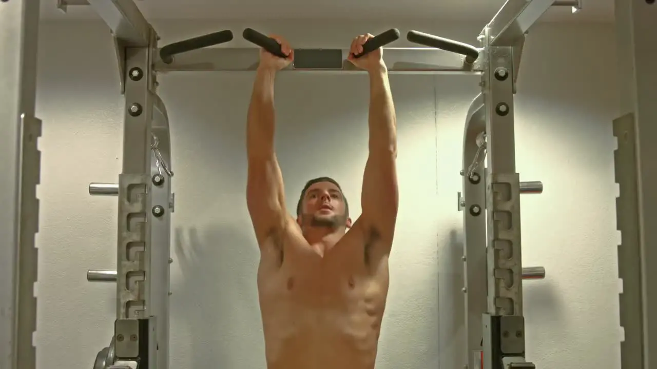 Fit man doing pull ups in fitness studio