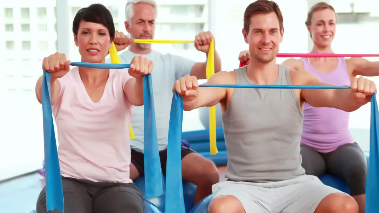 Group sitting on exercise balls stretching resistance bands