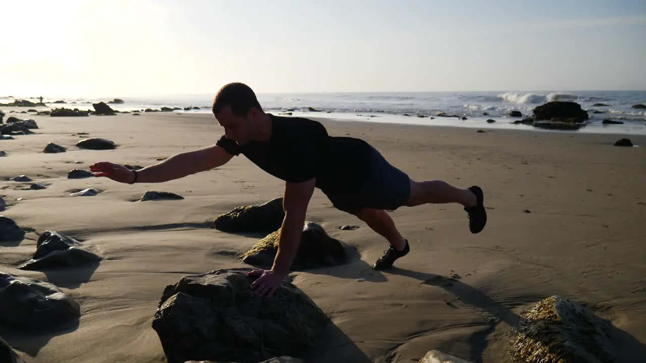 A strong man balancing in a yoga pose during a meditative workout at sunrise on a beach in Santa Barbara California SLOW MOTION