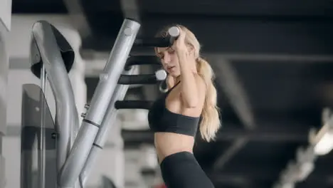 Sport woman doing pulling up exercise on fitness machine in modern gym