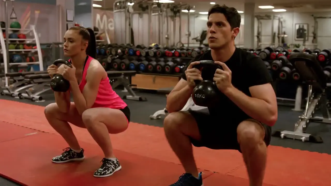 Couple doing weighted squats in gym