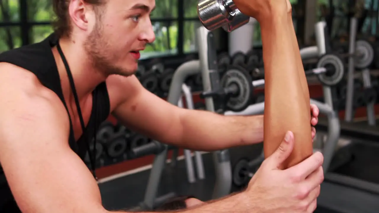 Muscular woman lifting dumbbell with her trainer