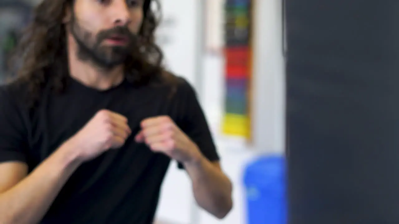 Man punching and kicking a striking bag in a martial arts school