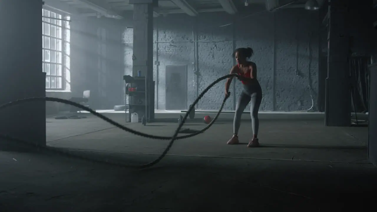 Woman doing workout with battle ropes Girl performing crossfit exercise