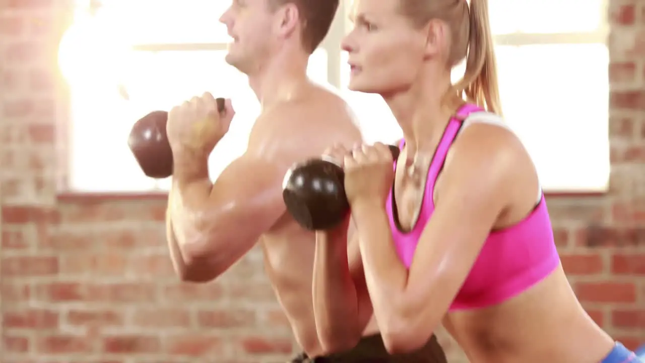 Fit man and woman using kettlebells