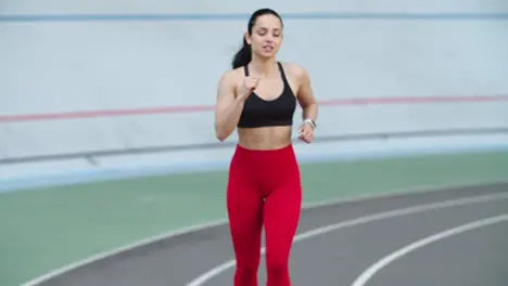 Woman training in sportswear on athletics track Tired fitness girl running