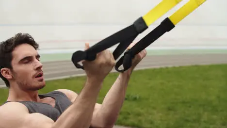 Muscular man exercising with fitness rope Guy working with fitness strap