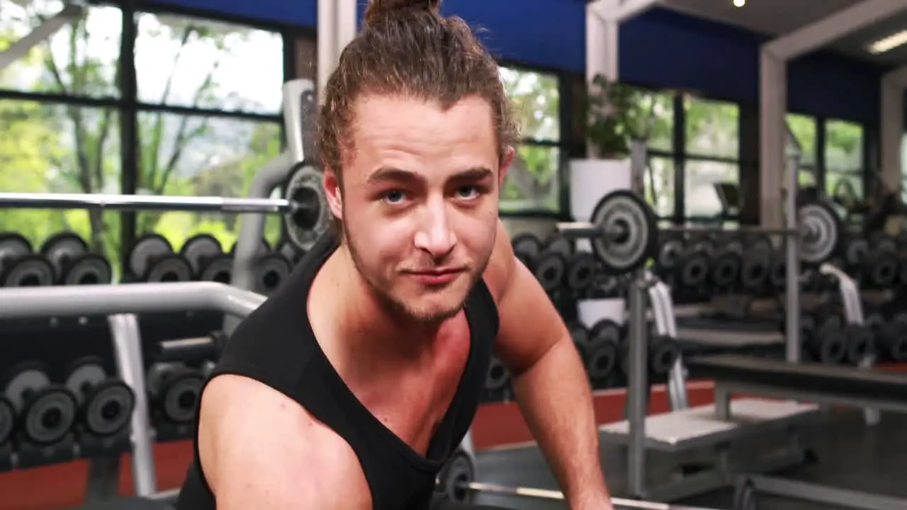 Smiling muscular man lifting dumbbell