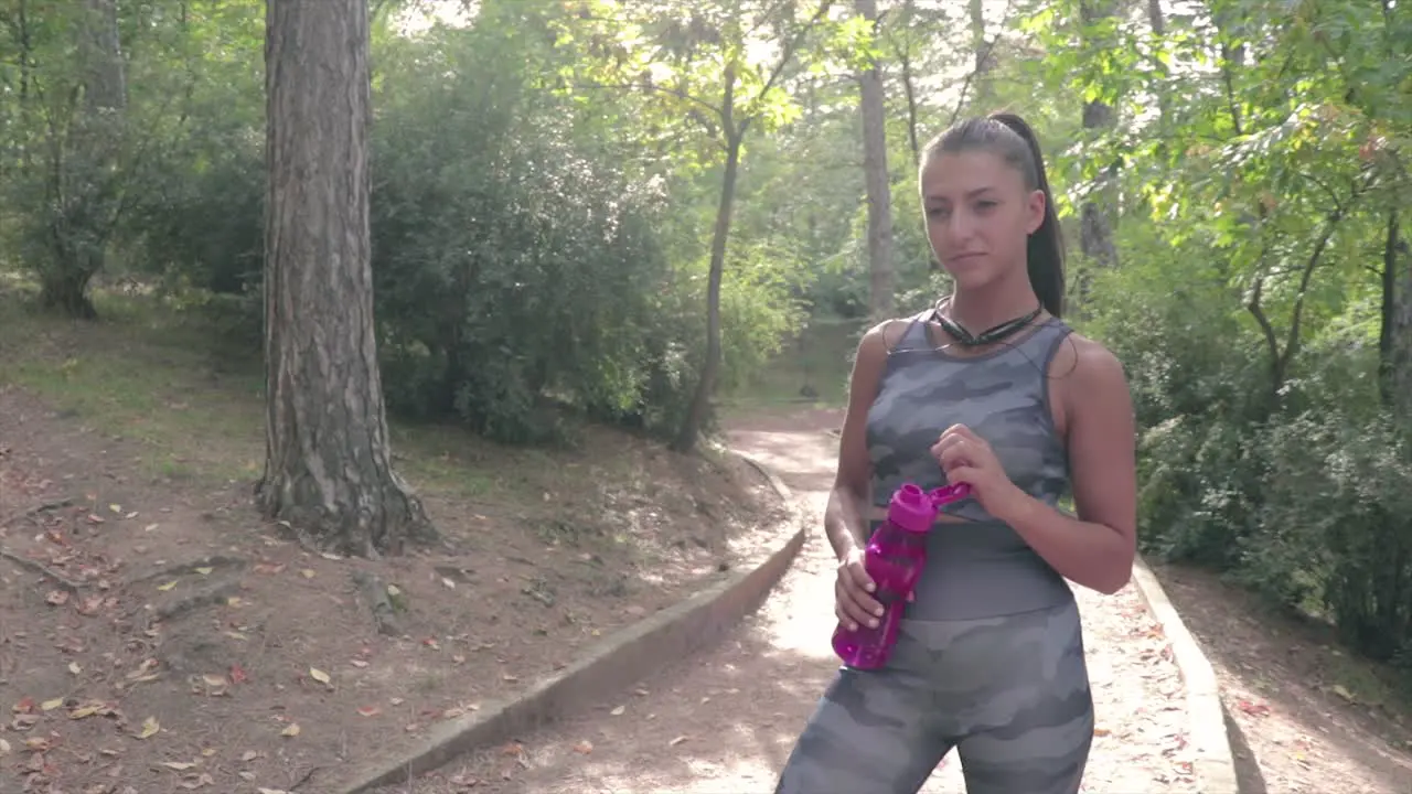 Girl drinking water while resting from a training in the park