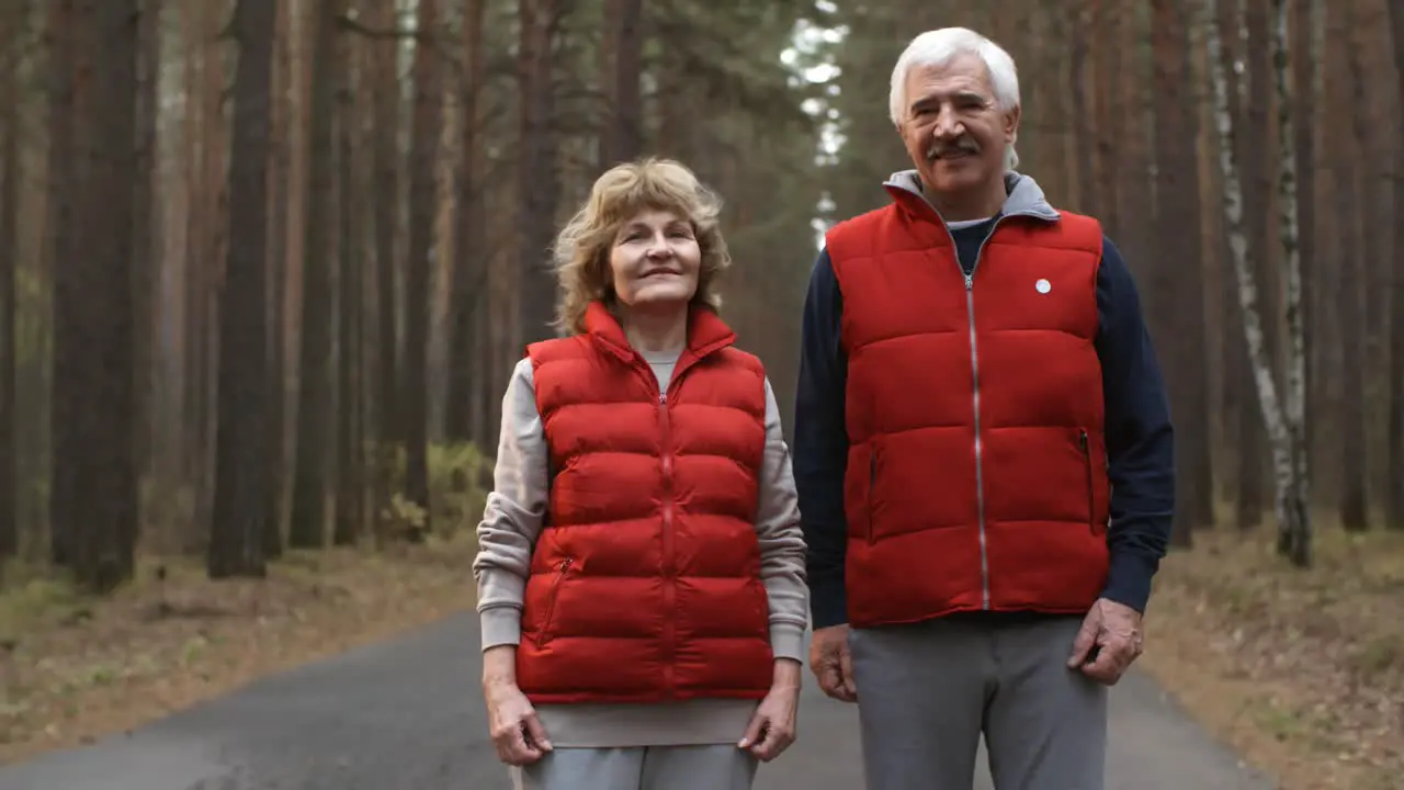 Happy Senior Couple In Sports Clothing Looking At Camera In The Forest