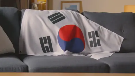 Flag Of South Korea Draped Over Sofa At Home Ready For Match On TV