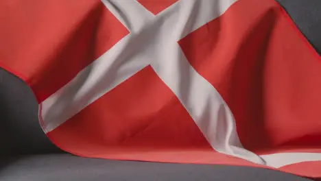 Close Up Of Flag Of Denmark Draped Over Sofa At Home With Football Ready For Match On TV