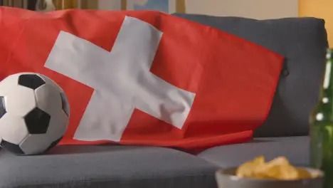 Flag Of Switzerland Draped Over Sofa At Home With Football Ready For Match On TV 1