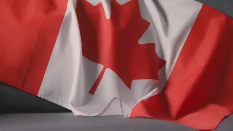 Close Up Of Flag Of Canada Draped Over Sofa At Home Ready For Match On TV 1