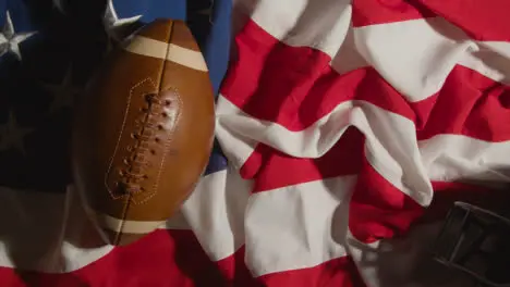 Overhead Shot Of Person Putting American Football Onto Stars And Stripes Flag With Helmet