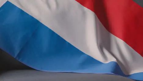 Close Up Of Flag Of Holland Draped Over Sofa At Home With Football Ready For Match On TV