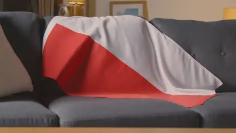 Flag Of Poland Draped Over Sofa At Home With Football Ready For Match On TV