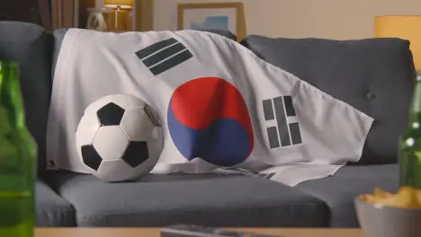 Flag Of South Korea Draped Over Sofa At Home With Football Ready For Match On TV