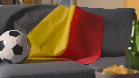 Flag Of Belgium Draped Over Sofa At Home With Football Ready For Match On TV 2