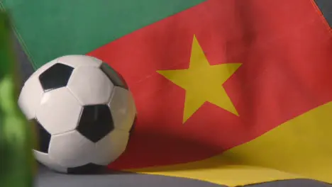 Flag Of Cameroon Draped Over Sofa At Home With Football Ready For Match On TV 2