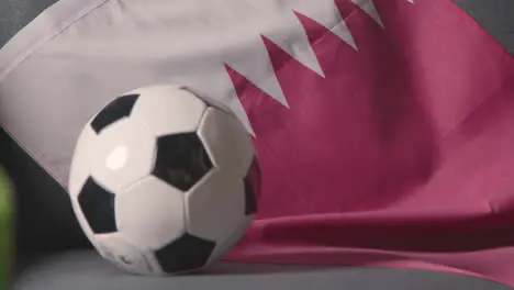 Flag Of Qatar Draped Over Sofa At Home With Football Ready For Match On TV