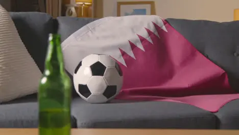 Flag Of Qatar Draped Over Sofa At Home With Football Ready For Match On TV 1