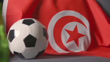 Flag Of Tunisia Draped Over Sofa At Home With Football Ready For Match On TV