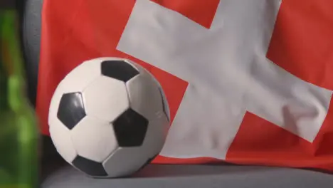 Flag Of Switzerland Draped Over Sofa At Home With Football Ready For Match On TV 2