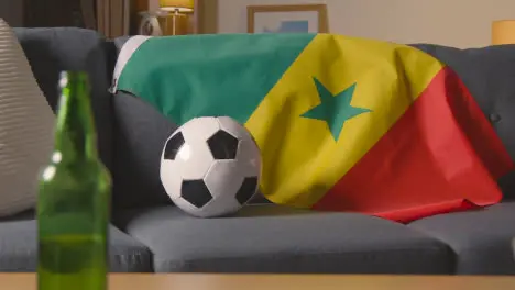 Flag Of Senegal Draped Over Sofa At Home With Football Ready For Match On TV