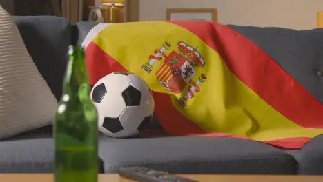 Flag Of Spain Draped Over Sofa At Home With Football Ready For Match On TV