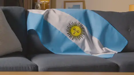 Flag Of Argentina Draped Over Sofa At Home With Football Ready For Match On TV