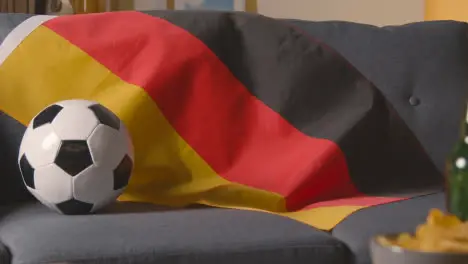 Flag Of Germany Draped Over Sofa At Home With Football Ready For Match On TV 1