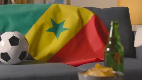 Flag Of Senegal Draped Over Sofa At Home With Football Ready For Match On TV 1