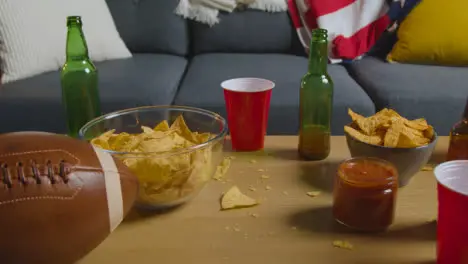 Lounge At Home Of Person Watching American Football Game On TV With Drinks Snacks And Ball