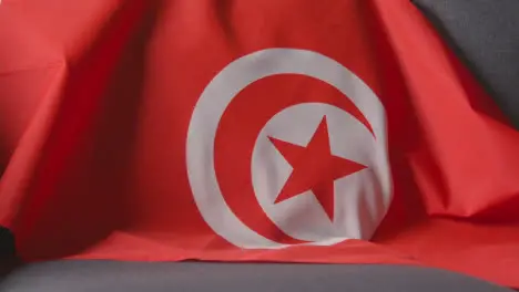 Close Up Of Flag Of Tunisia Draped Over Sofa At Home Ready For Match On TV