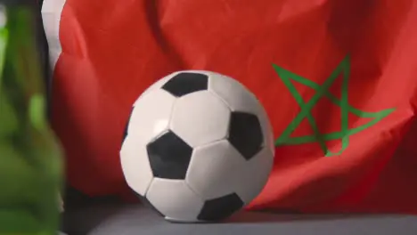 Flag Of Morocco Draped Over Sofa At Home With Football Ready For Match On TV