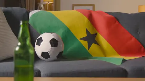 Flag Of Ghana Draped Over Sofa At Home With Football Ready For Match On TV 1