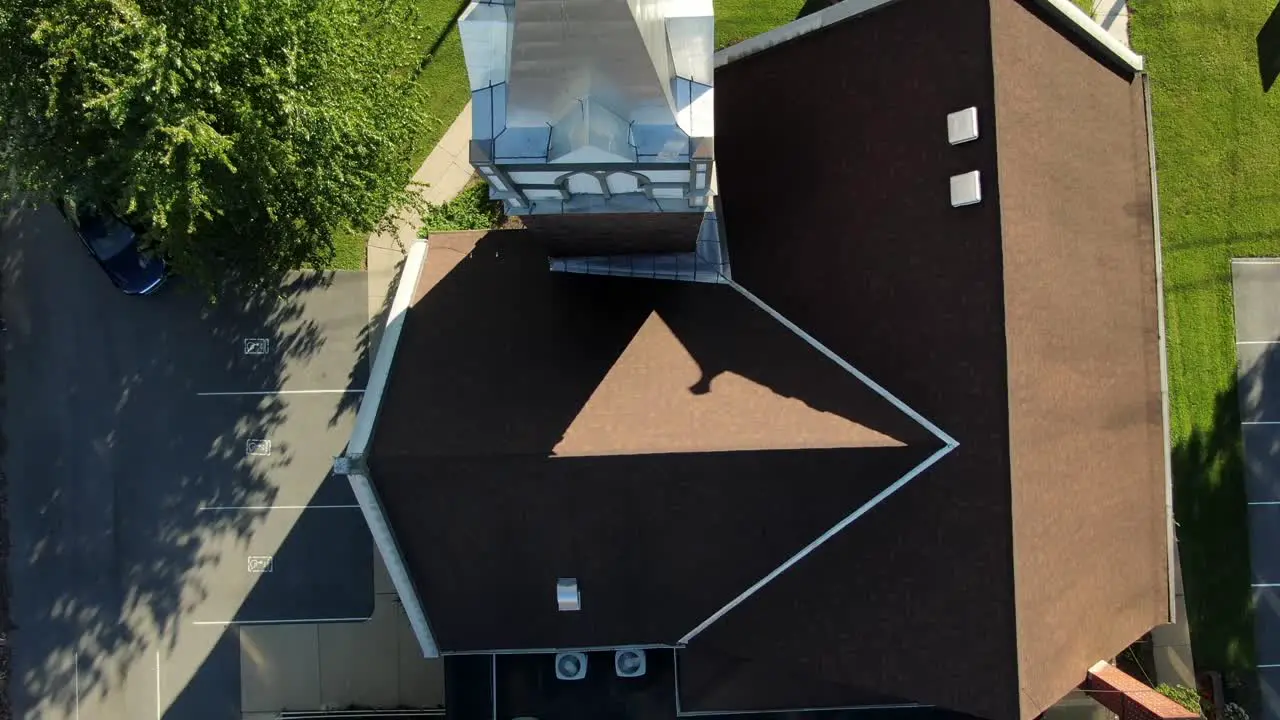 Overhead top down aerial of church and steeple roof contours and shadows during summer magic hour