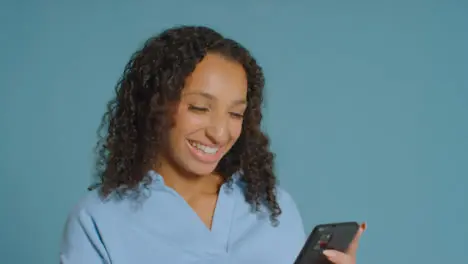 Portrait Shot of Young Adult Woman Smiling and Using a Smartphone