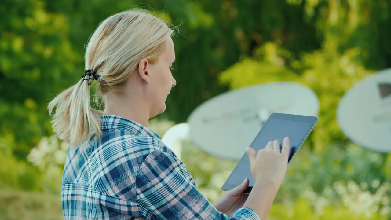 Woman Tunes Satellite Dishes Outdoors Uses Tablet