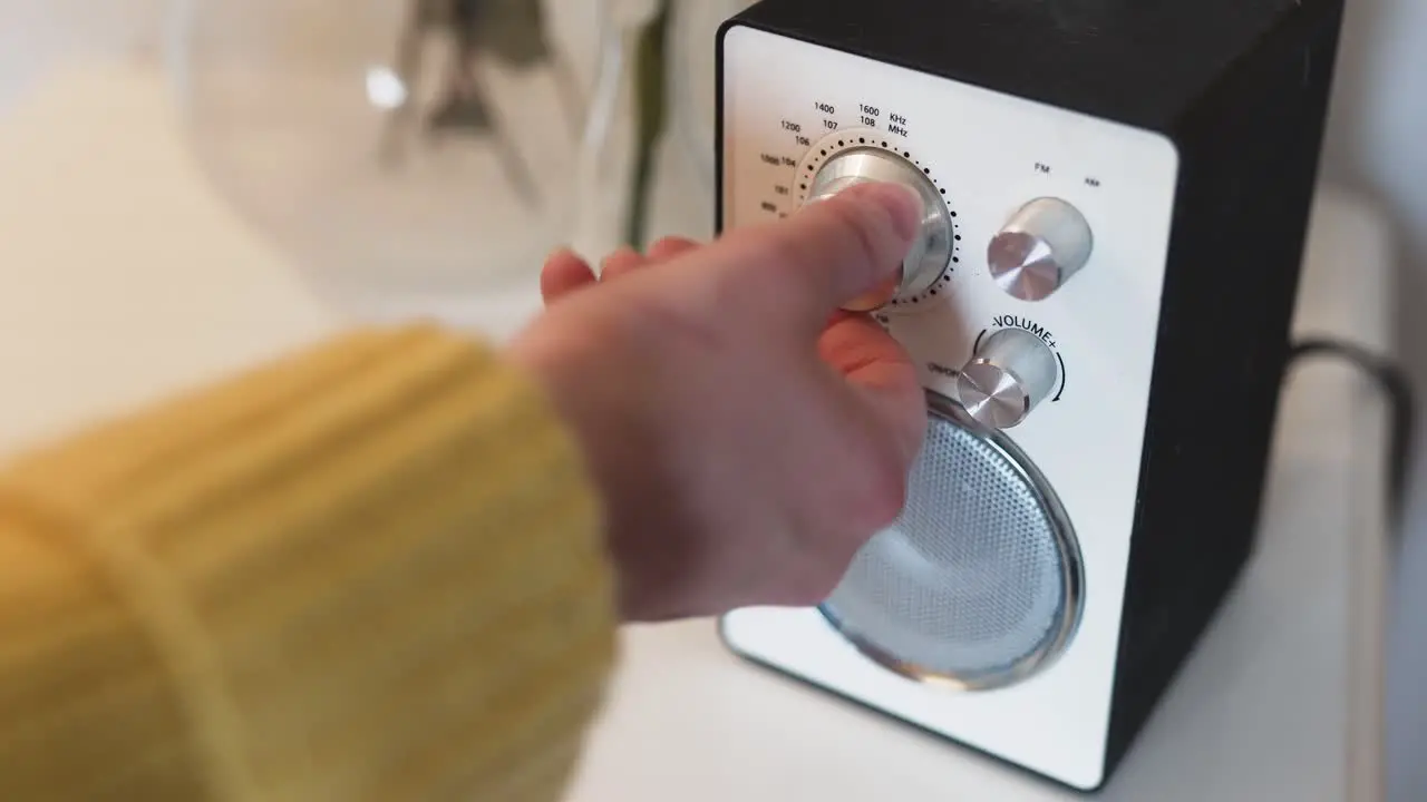 Showing a female wearing a yellow sweater tuning in the right frequency on her radio to listen to her favorite show