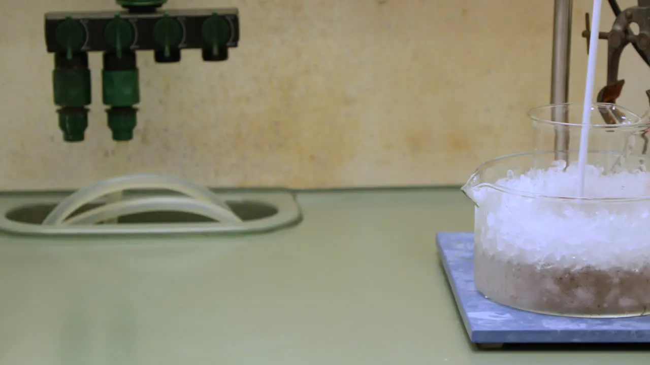 Stirring Chemical Solution In A Beaker Submerged In Ice For Cooling In Laboratory slider reveal