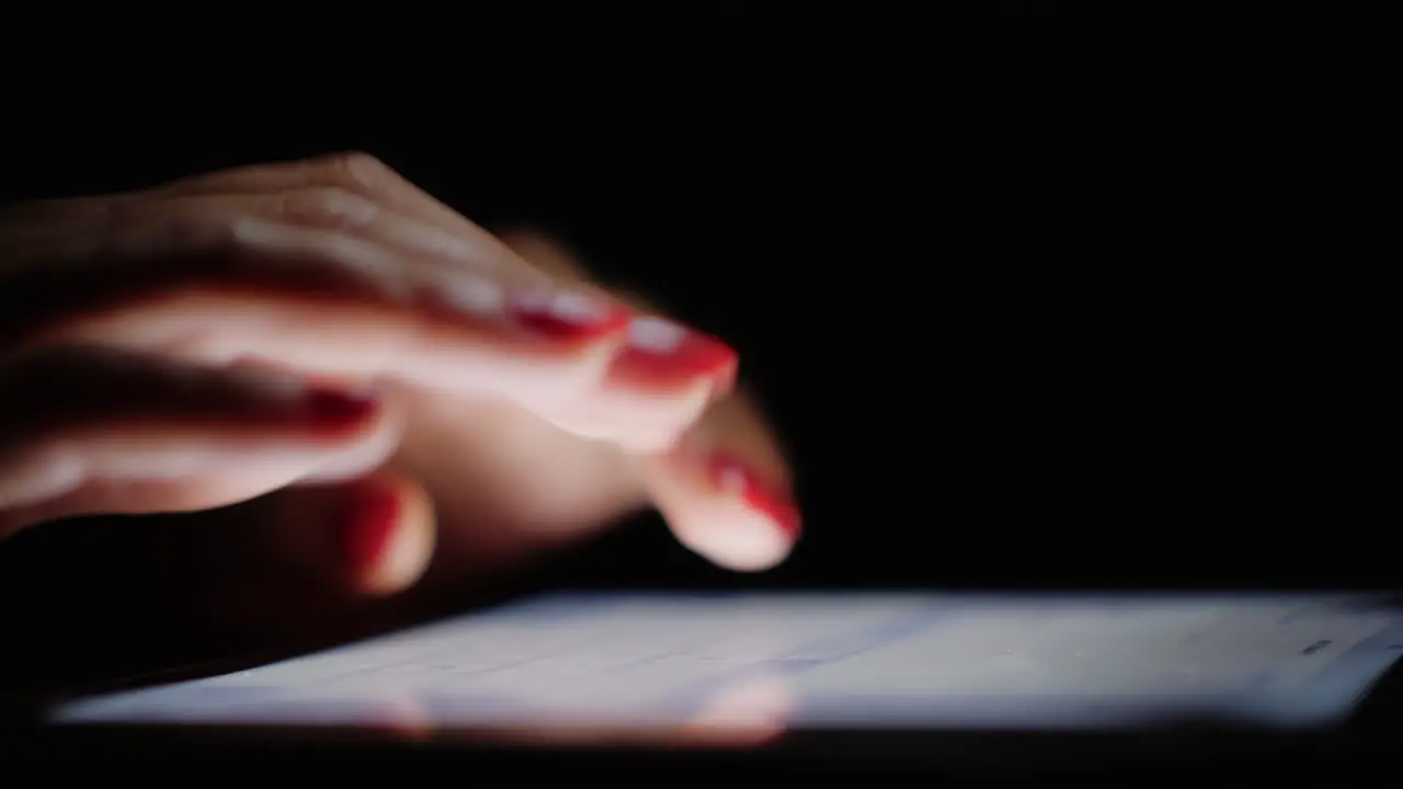 Female Fingers With Red Manicure On Their Nails Print Text On The Tablet At Night Close-Up 4k Video