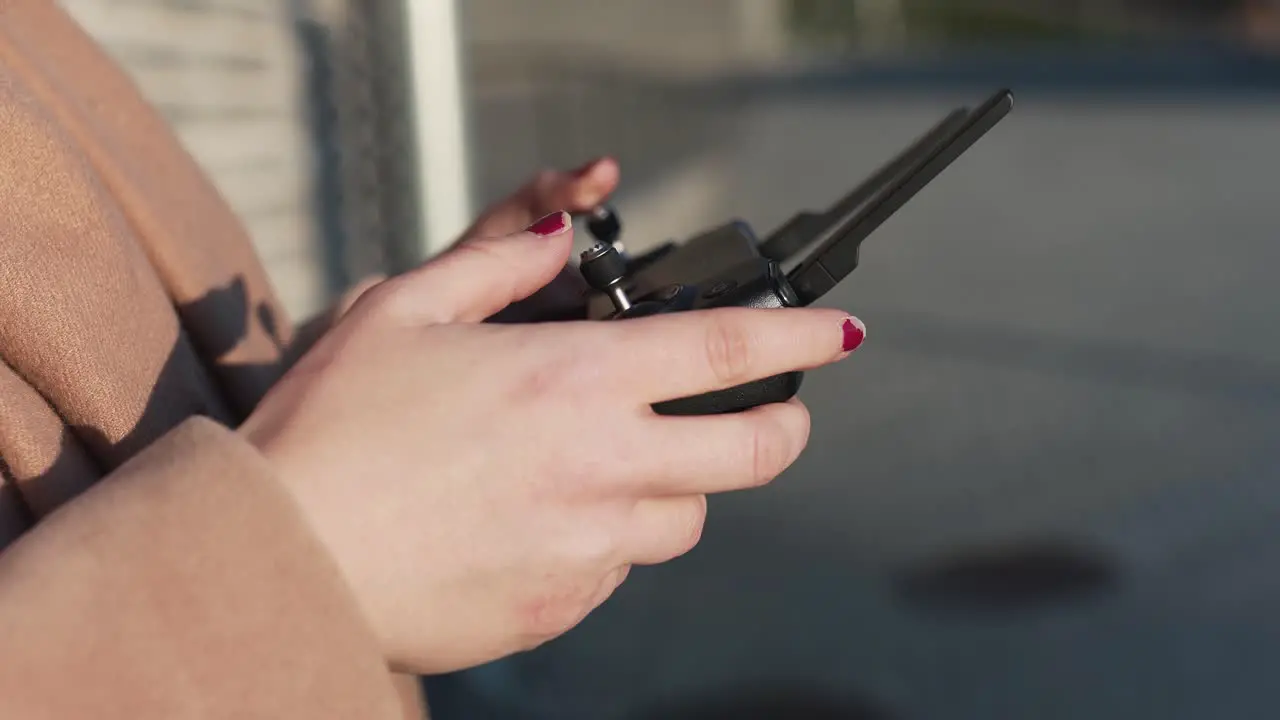 Closeup of female hand flying a drone in the middle of the day